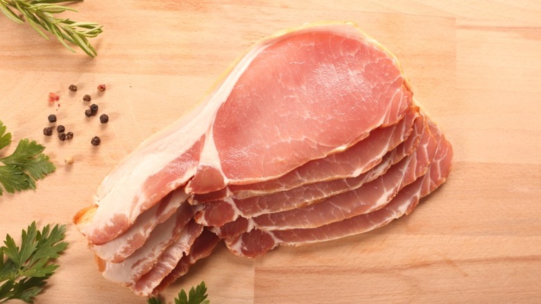 Slices of back bacon arranged on a wooden board