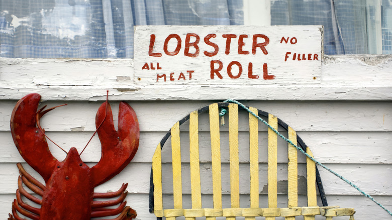 A close up of a handmade wooden sign for lobster rolls and a lobster figurine