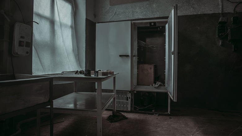 abandoned kitchen with fridge door open and empty table