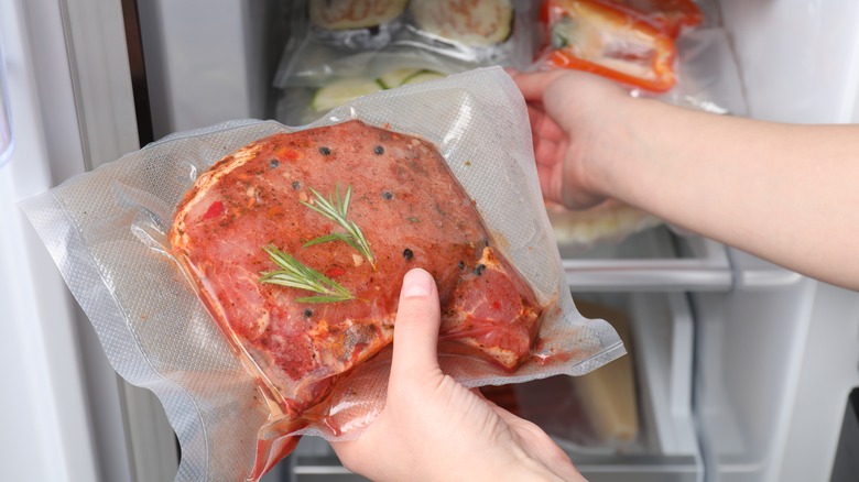 Person holding up a piece of meat in air tight packing