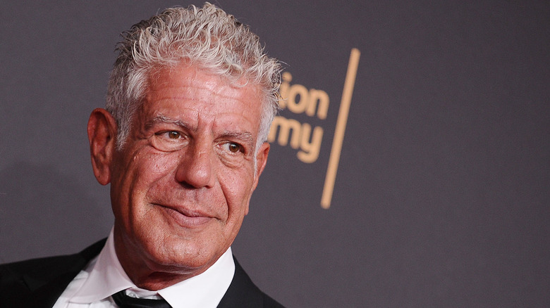 Anthony Bourdain poses at an event on a red carpet