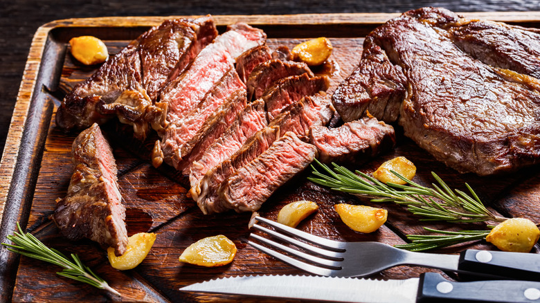 beef chuck eye steak sliced on a wooden tray