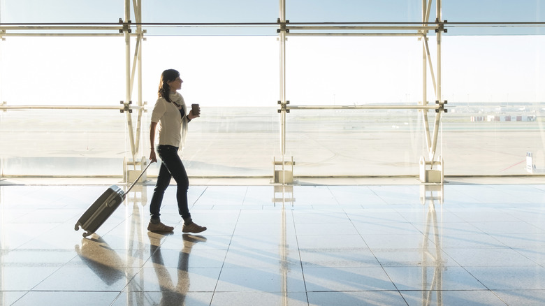 A woman with a suitcase walking through an airport