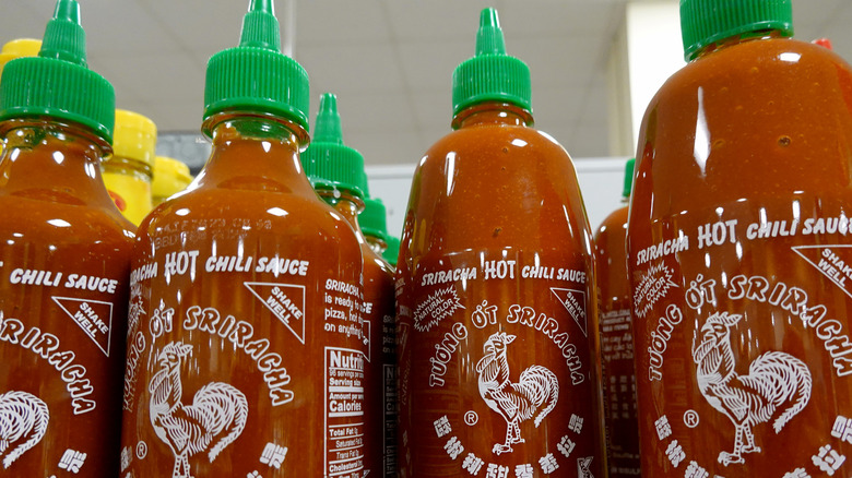 Multiple bottles of Sriracha sauce on a grocery store shelf