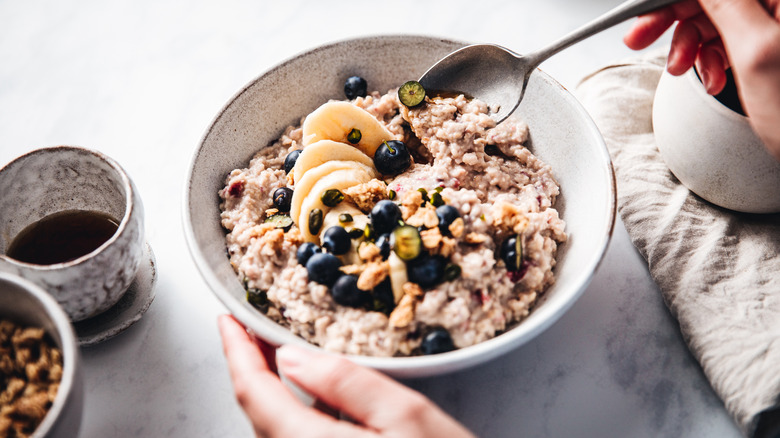 A bowl of oatmeal topped with sliced bananas and fresh blueberries