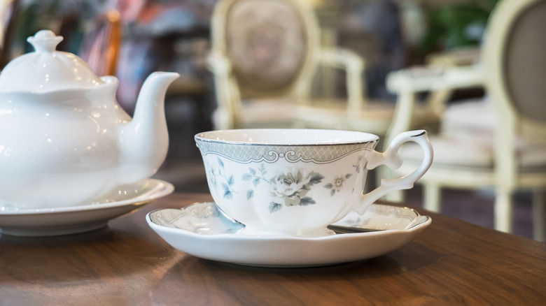 A tea cup and pot on a table.