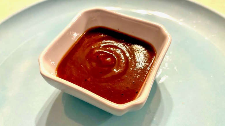 Barbecue sauce in a white ramekin on a blue plate