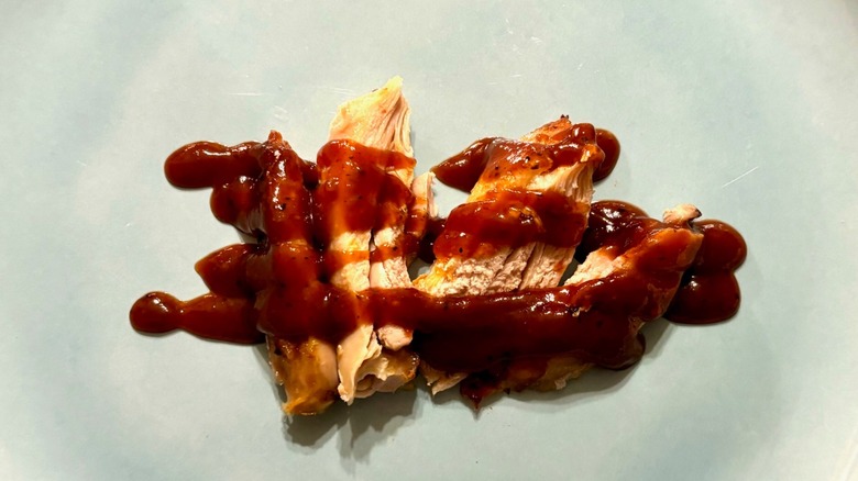 Sliced chicken meat with barbecue sauce drizzled on it