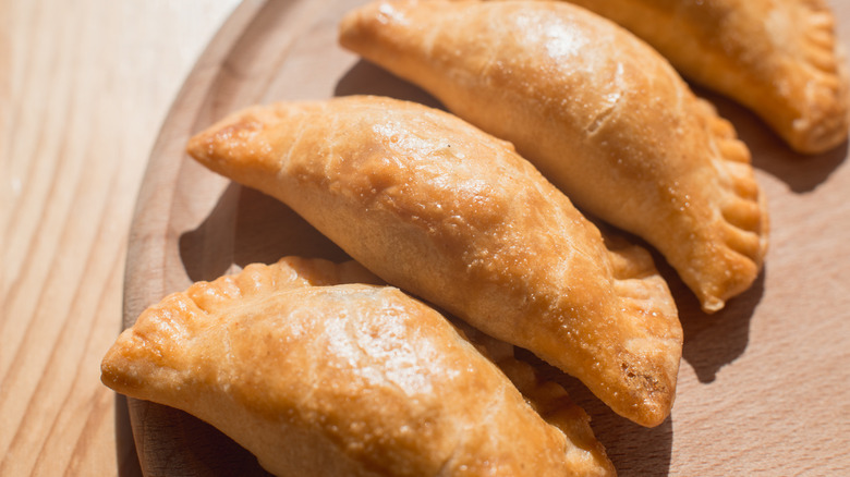 A row of empanadas sits on a plate