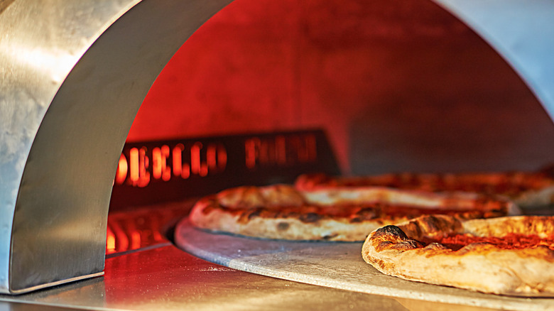 Two pizzas sitting on a pizza stone.