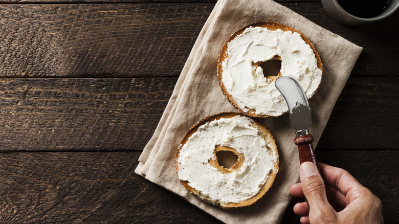 A bagel split in half and smeared with cream cheese