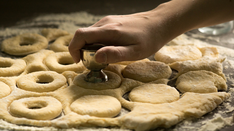 Hand punching holes in donut dough