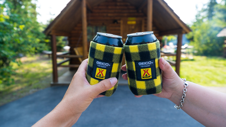 People cheers-ing beer cans in decorative koozies