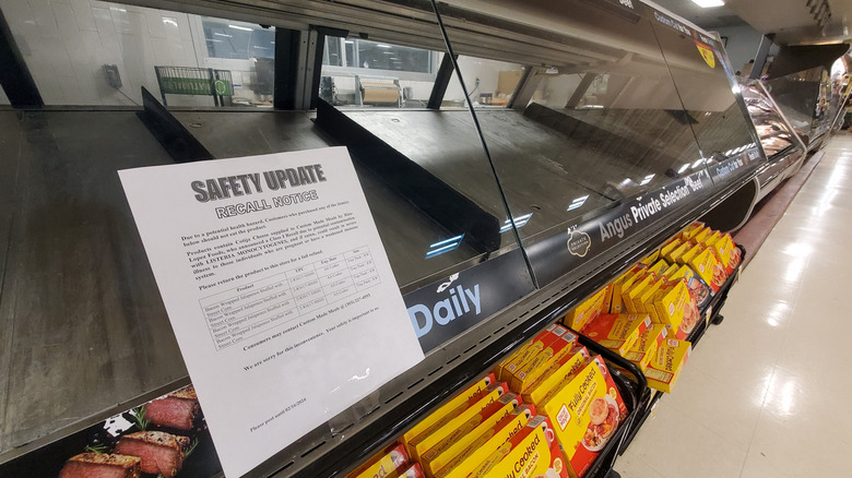 Empty deli case with a safety update notice on the front