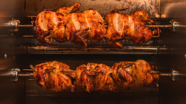 Six rotisserie chickens being cooked at once.