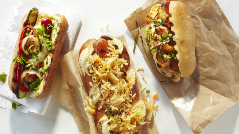 Three gourmet hot dogs with lots of toppings