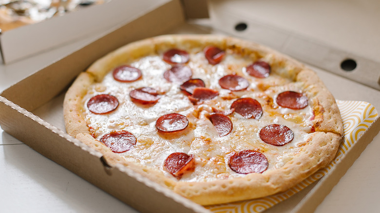 A greasy pepperoni pizza in a pizza box.