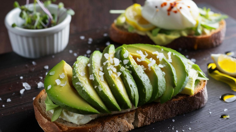 Toast with salted avocado slices sitting on top with herbs and salt in the background