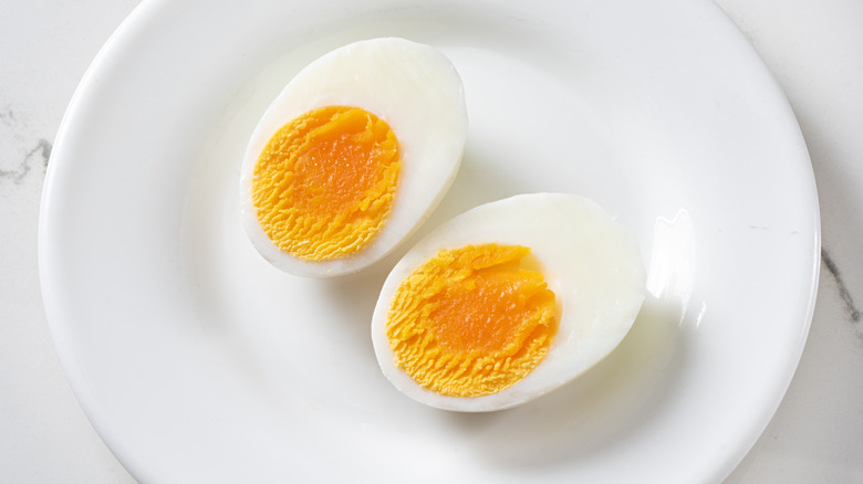 Two hardboiled eggs cut open on a white plate