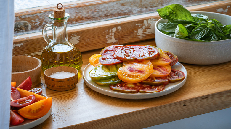 sliced beefsteak tomatoes on a plate with oil and salt