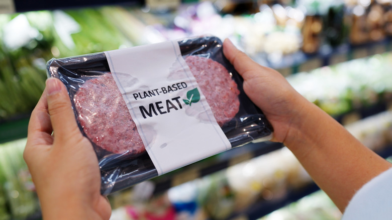 woman's hands holding packaged plant based burger patties