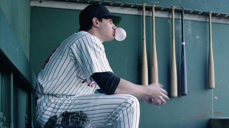 Baseball player blowing a bubble out of chewing gum on the bench