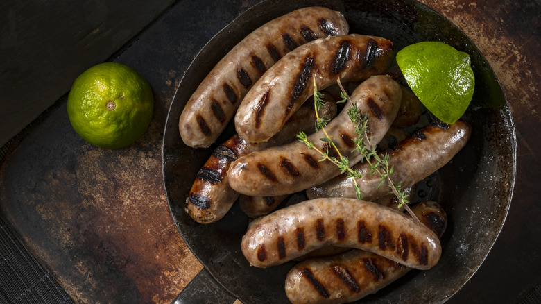 A pan holding grilled sausage and half a lime