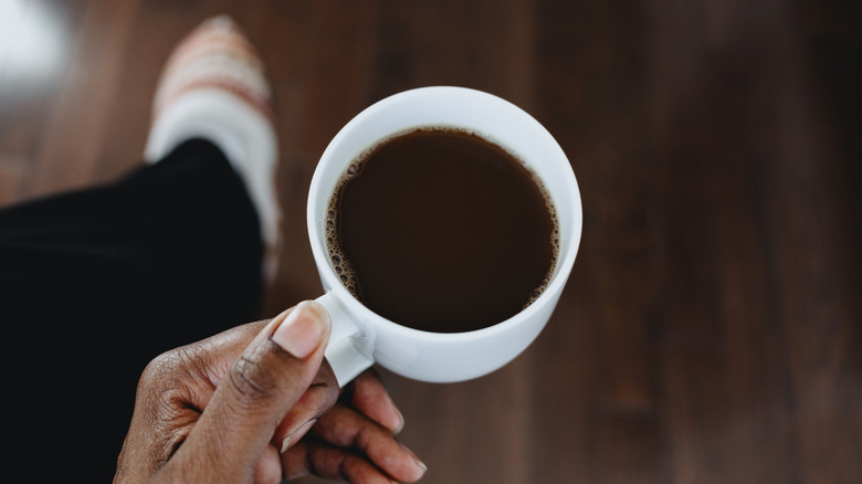 A hand holds a mug filled with coffee