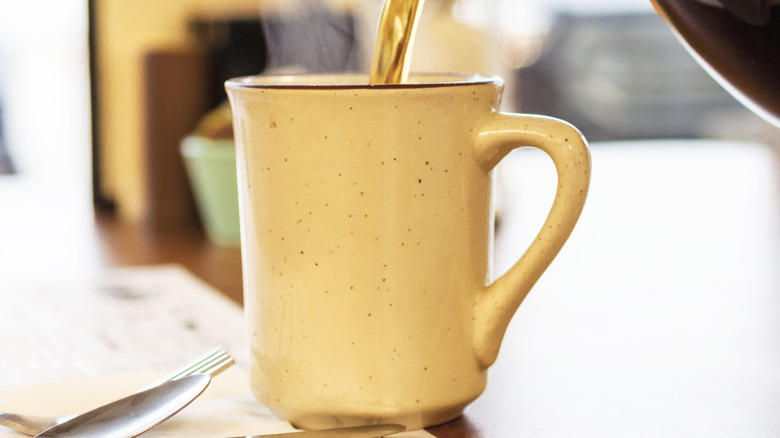 Coffee pouring into yellow mug