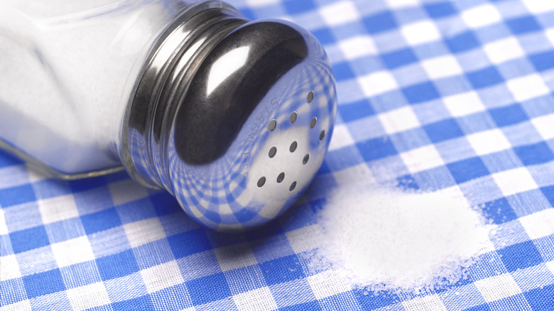 A spilled salt shaker on a tablecloth