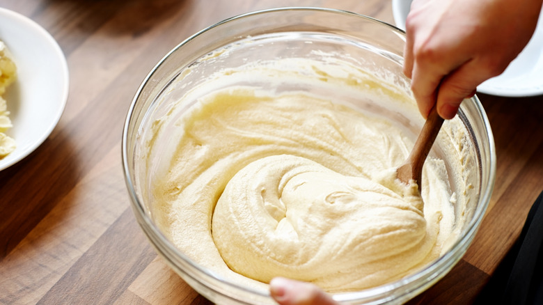 Someone stirring batter with a wooden spoon