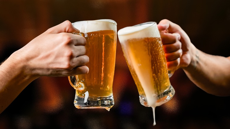 two people holding beer pints together