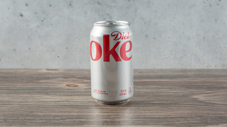 A can of Diet Coke placed on a wooden table.