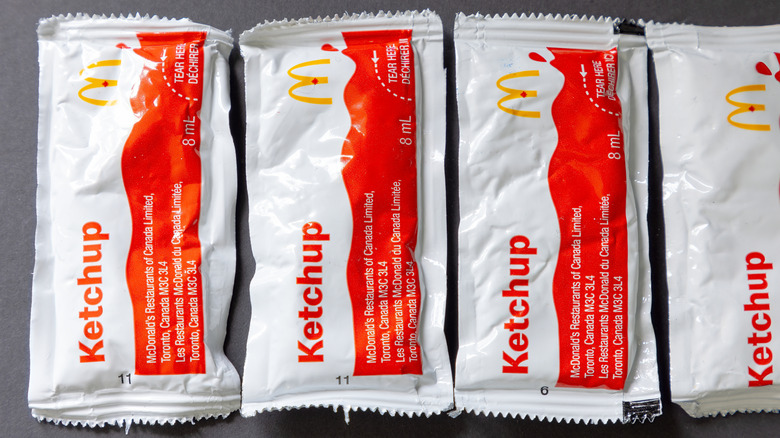 Four packets of McDonald's ketchup on a gray background