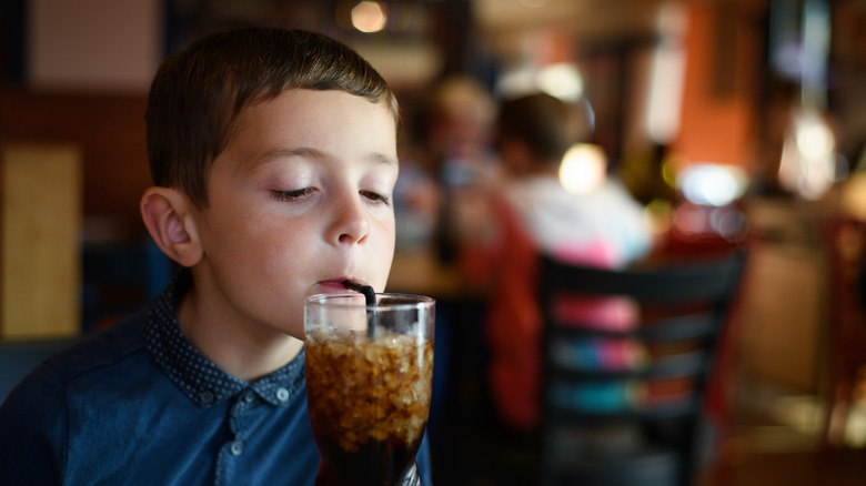 young boy sipping soda through a straw