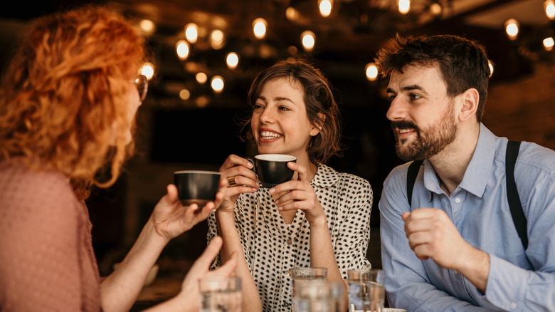 Three people drinking coffee in a restaurant.