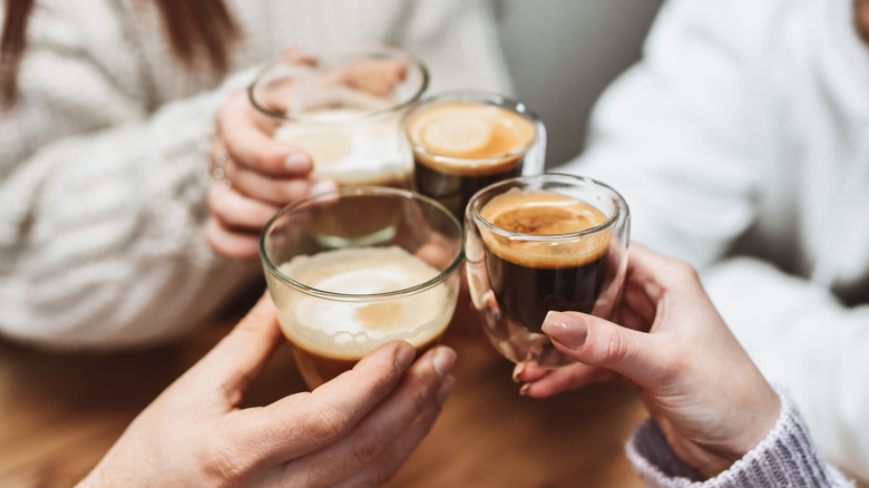 Four hands clinking espresso cups.