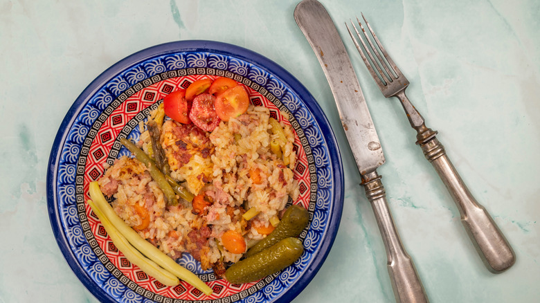 a plate with a rice dish and antique knife and fork next to it