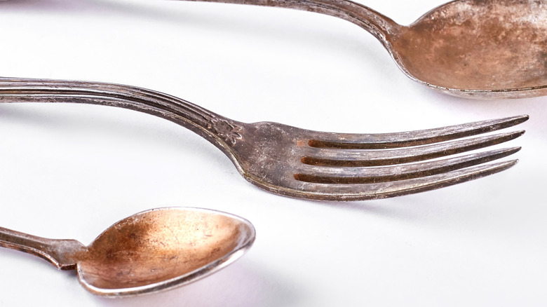 antique fork flanked on either side by rusted spoons