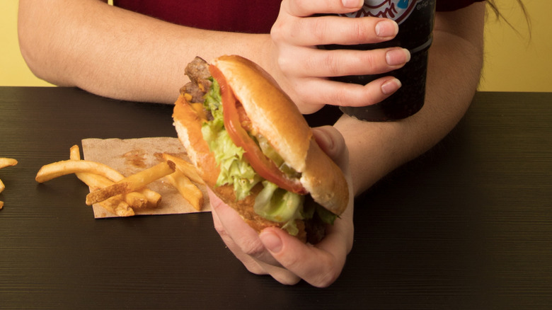 woman holding a soda and a wendy's burger