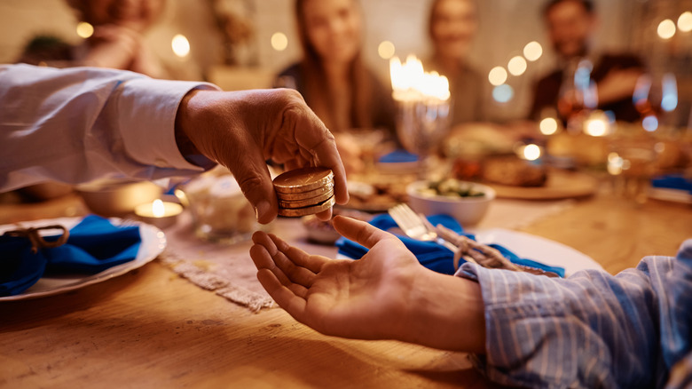 Two people exchanging gelt coins at Hanukkah