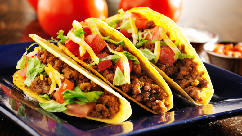 Three beef hard shell tacos on a blue plate