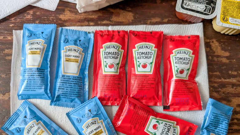 An assortment of condiment packets including ketchup and light mayo