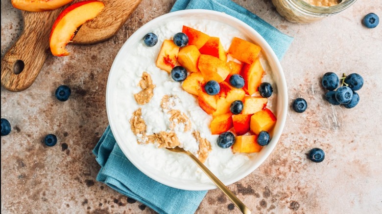 Bowl of cottage cheese with peaches, blueberries, and granola on top