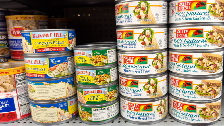 Stacks of canned chicken on grocery store shelves