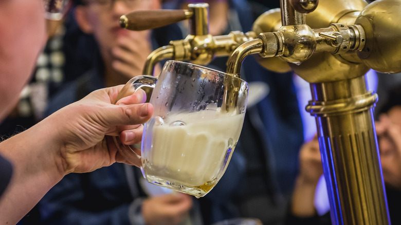 Glass of mlíko foamy beer being poured from the tap