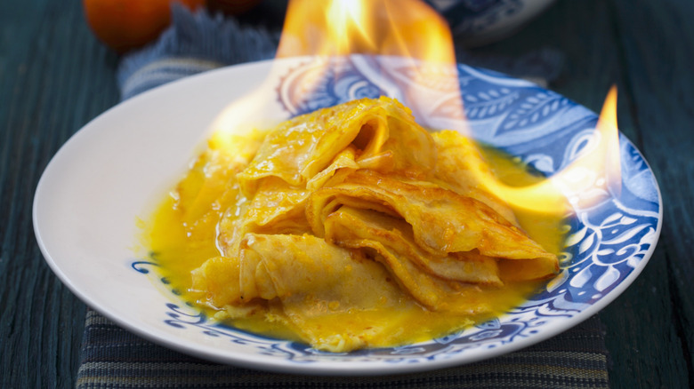 Crepes Suzette, flaming on a blue and white patterned plate