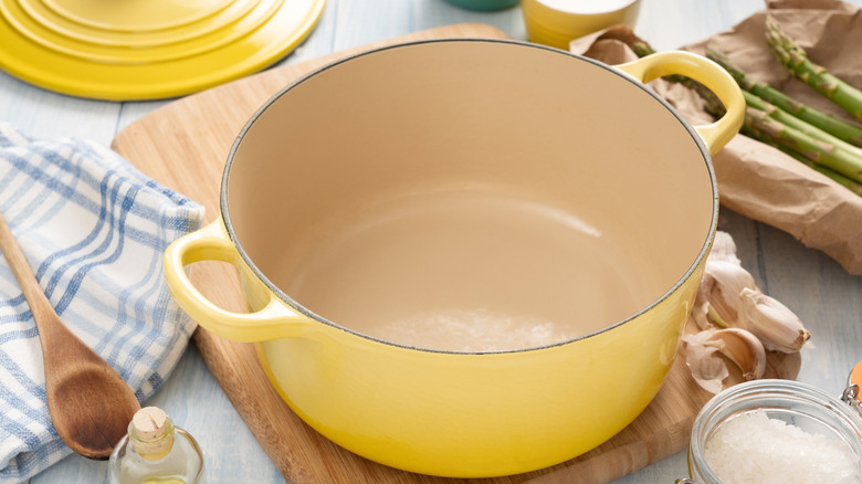 Yellow Dutch oven on cutting board with lid off