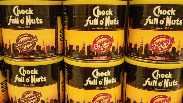 Six cans of Chock Full o' Nuts coffee on a supermarket shelf.