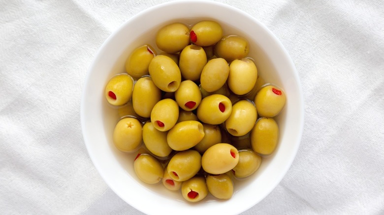 pimento-stuffed green olives in a white bowl with brine